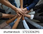 Close up mixed race business people putting hands together, support and unity concept. Diverse colleagues joining in team building activity, staff training concept, start working together, teamwork.