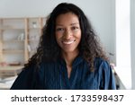 Close up headshot portrait picture of smiling african american businesswoman. Happy attractive confident young diverse woman mentor looking at camera on workplace background in coworking office.