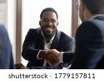 African Caucasian businessmen in formal suits express respect shake hands start negotiations. Common project growth sales increase, partnership, business etiquette, leadership, racial equality concept