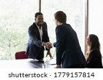 Small photo of Mixed race and Caucasian business partners start group meeting shake hands express regard. Happy candidate get hired job interview accomplish. Gesture of approval acceptance, business promises concept