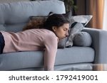Exhausted young Caucasian woman lying on comfortable sofa in living room sleeping after hard-working day, tired millennial female fall asleep on couch at home, take nap or daydream, fatigue concept
