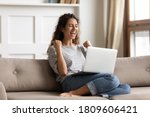 Woman sit on sofa put pc on lap clenched fists scream with joy while read great news on laptop. Gambler celebrate online auction bet victory. Got incredible offer sincere emotions of happiness concept