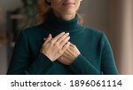 Small photo of Crop close up of Caucasian woman hold hands in prayer at heart chest feel religious superstitious. Young female believer being grateful thankful pray to God. Faith, belief, religion concept.