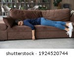 Small photo of Exhausted millennial Indian woman lying on sofa in living room sleep or take nap. Tired young mixed race ethnicity female renter doze off fall asleep on couch at home. Tiredness, fatigue concept.