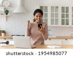 Overjoyed hispanic woman student on distant learning receive text message on cell with good exam results. Happy female freelancer celebrate getting money reward positive feedback for work from client