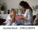 Small photo of Loving young Hispanic mother congratulate excited small daughter with birthday give wrapped gift. Caring happy Latin mom greeting make surprise with present for little girl child, celebrate together.