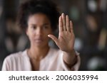Close up of African American woman showing stop gesture with hand blurred background, young female protesting against domestic violence and abuse, bullying, saying no to gender discrimination