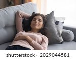 Peaceful woman closed her eyes take break lying sleeping on comfy couch having day nap resting alone in living room, breath fresh conditioned air, reduce fatigue, relish day off at modern home concept