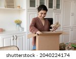 Small photo of Easy food shopping. Satisfied young indian woman loyal internet market customer unpack box with groceries ordered online. Smiling mixed race lady buyer get good quality foodstuff by courier delivery
