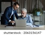 Small photo of Modern tech in office. Skilled millennial ceo team leader explain work in corporate application on laptop to mature male colleague. Young man assist aged manager workmate in doing electronic paperwork