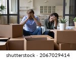 Small photo of Exhausted young couple sit rest on sofa in living room near heap of cardboard boxes feel unmotivated to unpack their belongings. Financial problem, debt and eviction, hard long relocation day concept