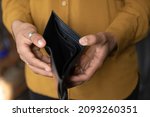 Small photo of Close up young African American unemployed woman holding opened empty black leather wallet. feeling stressed without cash, having financial problems, suffering from lack of money, bankruptcy concept.