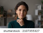 Small photo of Head shot portrait beautiful calm woman touching chin, feeling self confident at home, rental tenancy concept. Happy attractive positive lady with perfect teeth and tidy hairstyle looking at camera.
