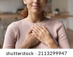 Small photo of Close up cropped view young attractive Hispanic woman stand alone indoor put folded palms on chest feeling grateful and appreciation, express sincere feelings. Believe, charity, body language concept