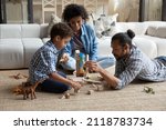 Small photo of Happy caring loving young African American couple parents playing wooden toys with small cute multiethnic child son, enjoying creative playtime activity together in modern living room, childcare