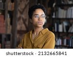 Serious young African business woman in casual glasses head shot portrait. Thoughtful Black businesswoman looking away with pensive face, dreaming, thinking over project tasks, problem solving