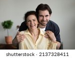 Small photo of Grateful loving grown son embracing happy senior mom with tenderness, care, affection, looking at camera, smiling, laughing. Mature mother and adult child head shot portrait. Motherhood concept