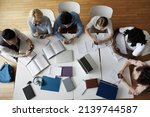 Small photo of Overhead view group of multi ethnic students use smartphones sit at shared table in classroom. Mobile application usage at break, young gen Z modern wireless tech overuse, bad habit, lifestyle concept