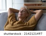 Small photo of Peaceful sleepy middle aged woman resting on sofa with closed eyes, falling asleep, enjoying break, silent leisure time at home, taking deep breath of fresh air, reducing stress
