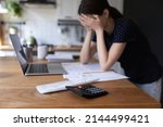 Close up view calculator and bills on table, desperate young woman on background, makes expenses and earnings analysis feels tired and disappointed. Lack of money, overspend, debt, financial troubles