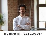 Small photo of Head shot young millennial Hispanic confident man. Handsome brunette guy pose alone at workplace or loft apartment look at camera. Professional occupation, freelance portrait, homeowner person concept