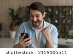 Oh yeah. Euphoric bearded male look at cell screen open mouth read exciting great news receive money present gift online. Overjoyed young male winner raise fist get victory at professional web contest
