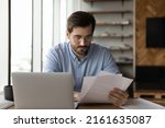 Small photo of Focused businessman reviewing paper reports, received letter, notice from bank, working at office workplace with laptop. Legal expert, professional, lawyer reading, checking financial documents