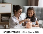 Happy excited Indian mother and kid dropping cash into piggybank. Caring mom teaching kid to save, invest money, collecting coins in piggy bank. Family savings, financial education concept