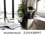 Back view of tired businessman sit lean in chair in office relax relieve negative emotions after working day. Exhausted calm male employee rest at workplace, daydream or nap. Stress free concept.