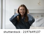 Small photo of Cheerful beautiful 30s Caucasian woman home head shot portrait. Pretty lady in casual trendy overcoat, trench, coat looking at camera with toothy smile, laughing, adjusting long hair. Fashion