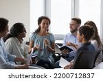 Small photo of Happy diverse addicts sitting on chairs in circle, talking on group therapy meeting, discussing addiction, mental health problems. Multiethnic employees brainstorming on team training