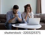 Small photo of Frustrated worried millennial husband and wife reading bankrupt message, blocked account notice, feeling concerned about overspent budget, lack of money, getting bad news, paying bills