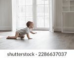 Small photo of Adorable baby wearing white bodysuit, crawling on knees on floor at home. Curious active little infant child learning to move on warm heating safe floor, passing by window in background