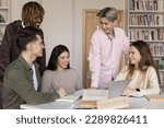 Small photo of Five happy diverse teenage students gather together, smile, laugh, enjoy talk, distracted from studying, blab seated at desk stand in library, engaged in teamwork, share ideas and opinion over task