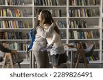 Small photo of Two pretty student girls, best friends schoolmates meets in college library hugging, express amity, glad to see each other feel happy, having good, warm relation. Friendship, relationship, studentship