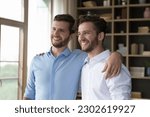 Small photo of Cheerful handsome young adult twin brothers posing for shooting together, standing close, hugging, patting shoulders, looking away, smiling, laughing, enjoying friendship