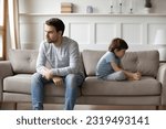 Small photo of Unhappy young Caucasian man father and little 6s son sit separate ignore each other after family fight. Upset stubborn dad and small boy child avoid talking having quarrel. Generation gap concept.