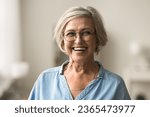 Small photo of Cheerful pretty blonde older woman in elegant glasses looking at camera with beautiful toothy smile, laughing , showing white perfect teeth, posing for elderly female head shot portrait