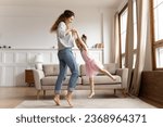 Small photo of Happy young mother dancing swirling with excited little preschooler daughter relaxing together in living room, overjoyed millennial mom or nanny have fun with small girl child playing at home