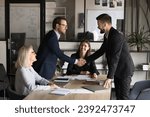 Small photo of Two happy confident business partners men shaking hands over large table, meeting with project colleagues, managers, closing deal, contract, discussing investment to startup, partnership