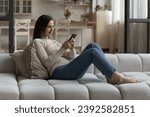 Small photo of Pretty woman chat on-line via social media networks use cellphone resting seated on sofa at home, spend weekend on internet. Young gen and modern tech, remote communication, mobile apps usage concept