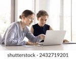 Small photo of Two young office employees working together use laptop, workmate helps to apprentice with corporate program, new app, software, telling about project, explain task, engaged in teamwork. Apprenticeship