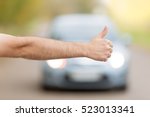 Close up of male hand hitchhiking, asking a coming car for a ride on summer street 
