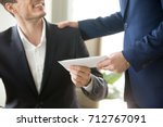 Company leader giving money bonus in paper envelope to happy smiling office worker, congratulating employee with increasing of salary or promotion, thanking for successes in work. Close up concept 