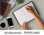 Woman hands writing on book in office.Business woman working on desk of wood.Business woman working with laptop and office supplies on top view.Copy space.