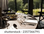 Luxurious Restaurant Table with shiny cutlery. Opulent Setting for Fine Dining Experience. High end restaurant. Romantic dinner in sunset light. Sunlight table. Vodka shot glass.