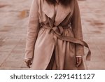 Small photo of Female figure in the brown long overcoat. Outdoor portrait in daylight. Autumn clothes street style concept. Film grain effect