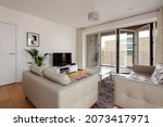 Small photo of Cambridge, England - Aug 6 2019 Modern city apartment Living room, simply decorated with Bifold doors opening to covered balcony.