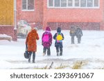 Blizzard in an urban environment, people, children walk home from school during snowfall in winter.