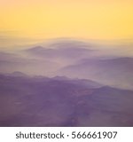 Small photo of Mountains and silhouettes of hills in haze and golden sunlight, yellow and purple tones. Magical landscape in a foggy morning - sunrise with upslope fog in mountain valley in pastel colors.